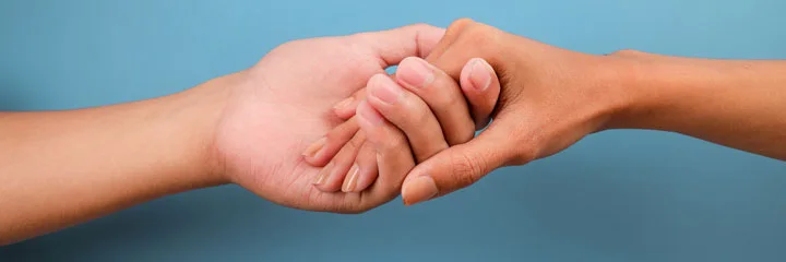two hands reaching out and clasping in front of a blue background