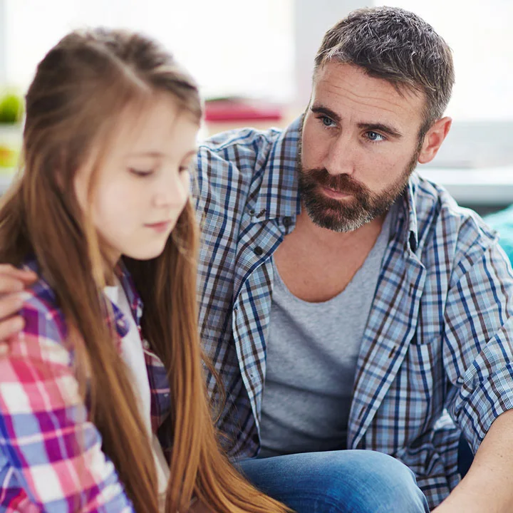 Young father with a beard consoling his tween daughter
