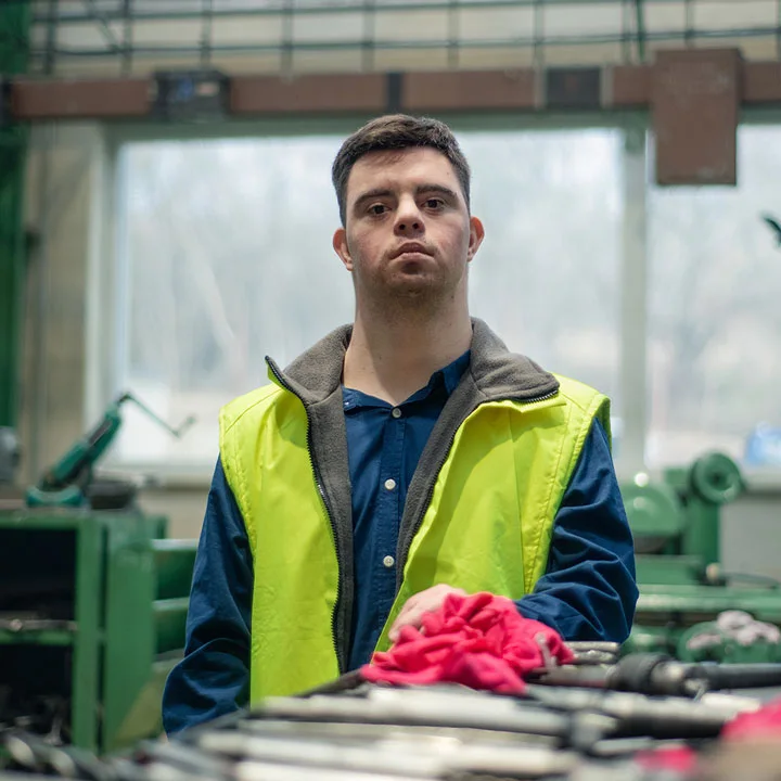 Young man with Down syndrome looking at blueprints when working in industrial factory