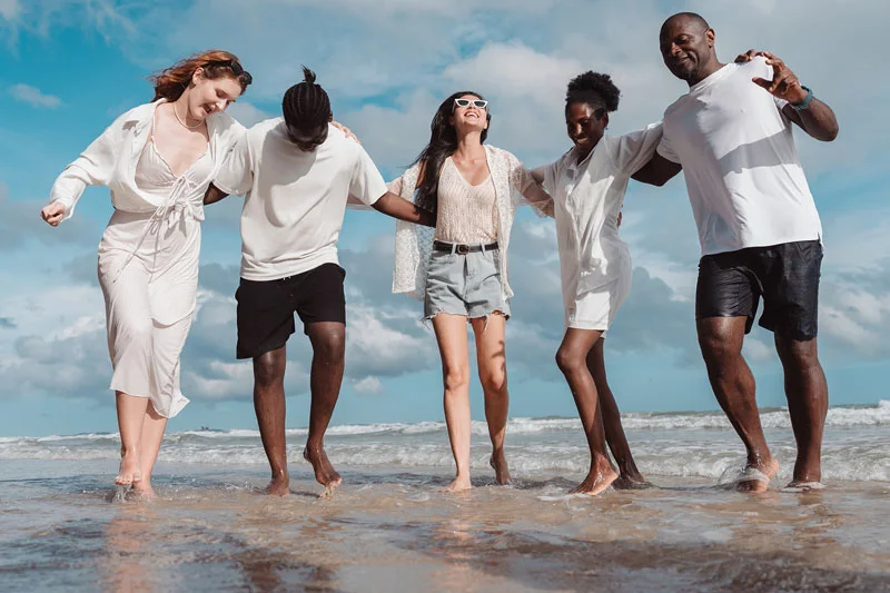 Happy diverse group of young adult friends together on the beach