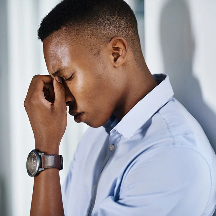 Attractive young black man looks grief-stricken and holds his face in his hand