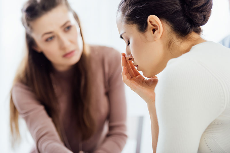 Young woman with dark hair consoles her female friend who seems upset